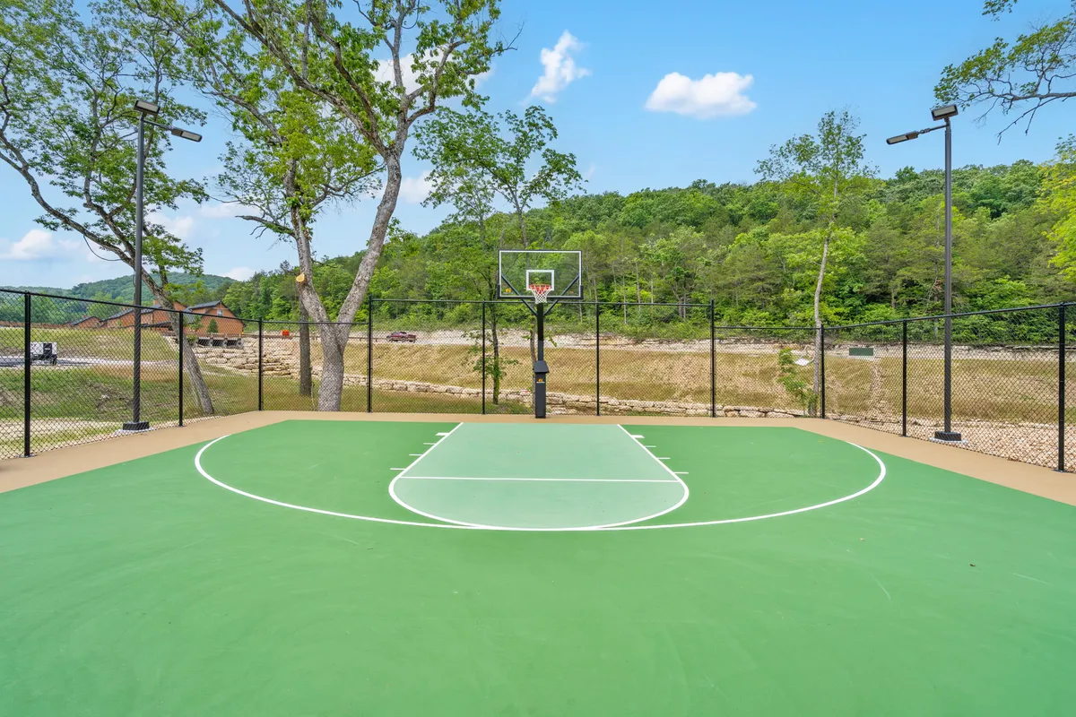An energetic outdoor basketball court bordered by trees and mountains in the distance. The open space invites guests to enjoy friendly games and active recreation amidst beautiful natural surroundings.