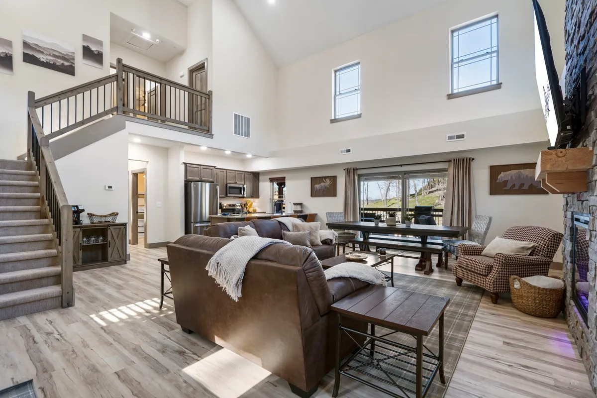 An open-plan view showcasing the dining table, kitchen area, and staircase, creating a sense of flow and togetherness. The dining table is ready for gatherings, while the kitchen sits conveniently nearby for easy meal service. The scene feels cozy and designed for connection, ideal for family meals or celebrations.