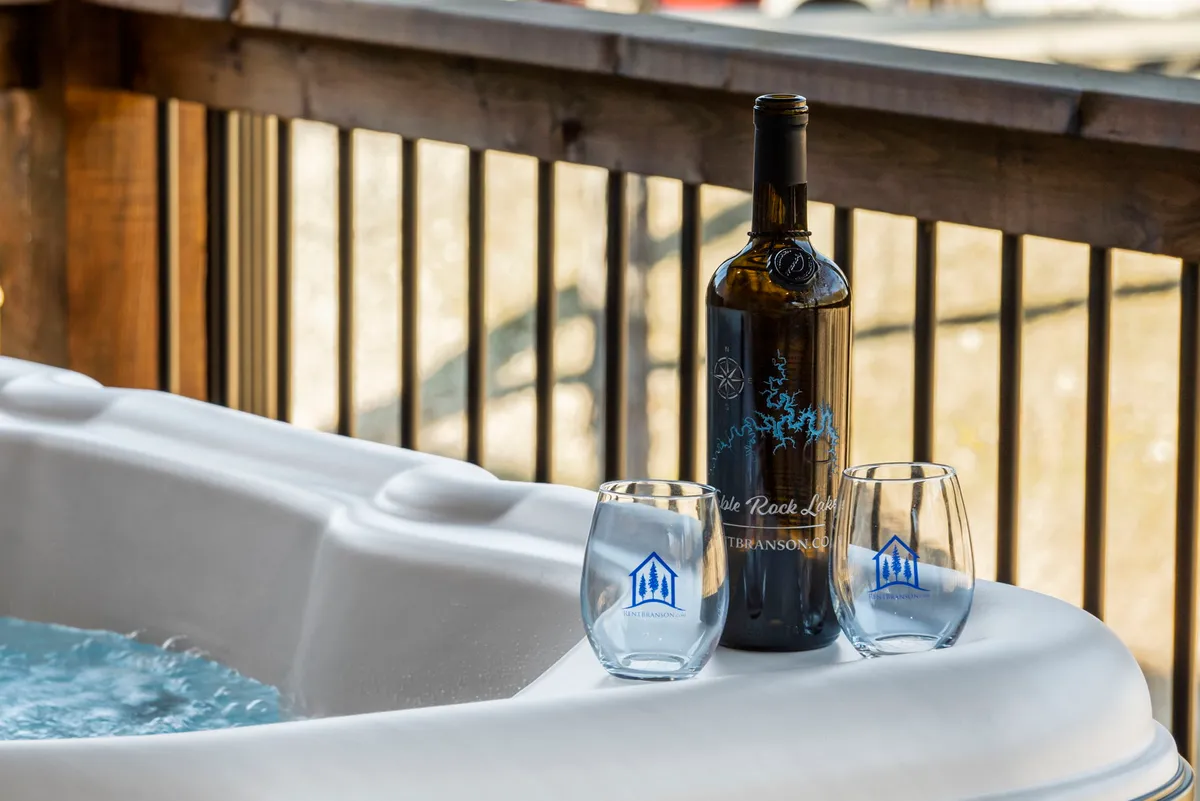 A relaxing hot tub on an outdoor deck, complete with wine glasses and a bottle of wine, surrounded by nature. The inviting setup is ideal for unwinding after an active day.